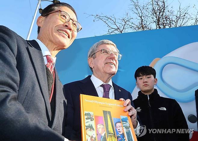 서울올림픽 책자 받은 바흐 위원장 (서울=연합뉴스) 서대연 기자 = 토마스 바흐 국제올림픽위원회(IOC) 위원장이 16일 오후 서울 송파구 올림픽공원 SK올림픽핸드볼경기장에서 열린 2024 대한민국 체육인대회에서 행사 시작에 앞서 조현재 서울올림픽기념국민체육진흥공단 이사장으로부터 서울올림픽레거시포럼 책자를 받고 기념사진을 찍고 있다. 2024.1.16 dwise@yna.co.kr