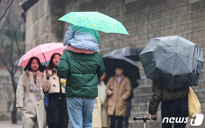 겨울비가 내린 14일 서울 중구 덕수궁 돌담길에서 우산을 쓴 시민들이 길을 지나고 있다. 2024.1.14/뉴스1 ⓒ News1 김도우 기자