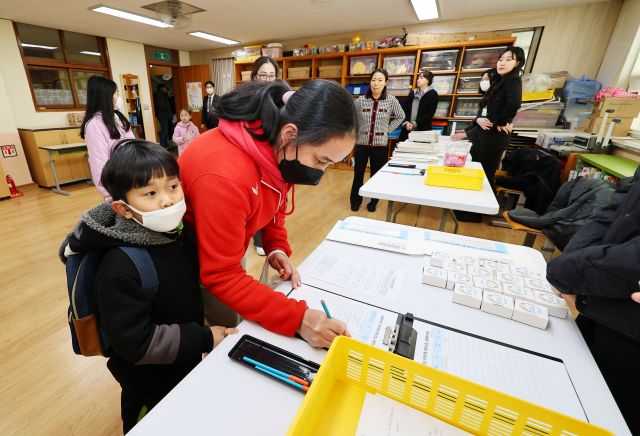 4일 오후 인천 동구 창영초등학교에서 열린 신입생 예비 소집에서 부모님과 예비 초등학생이 선생님의 안내를 받고 있다. 연합뉴스