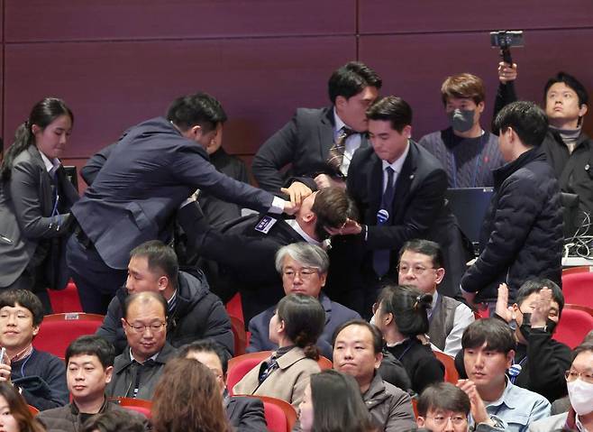 [전주=뉴시스] 전신 기자 = 강성희 진보당 의원이 18일 전주 덕진구 한국소리문화의전당 모악당에서 열린 전북특별자치도 출범식에서 윤석열 대통령이 참석자들과 인사하는 동안 경호원들에게 끌려 나가고 있다. 진보당측은 "강 의원이 윤 대통령과 악수하며 '국정기조를 바꾸지 않으면 국민들이 불행해집니다'라는 말을 건넨 순간 경호원들이 제지했다"고 주장했다. (대통령실통신사진기자단) 2024.01.18.