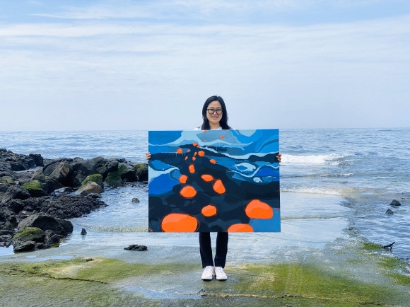 나경아 화가가 제주 서귀포 남원읍 태흥리 바다에서 물질하면서 그린 작품 ‘출근길’을 들고 활짝 웃고 있다. 작가 제공