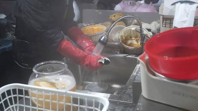 직원이 빨간 양념 등으로 오염된채 버려진 배달음식 용기를 설거지 하는 모습. 채반석 기자