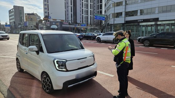 '우회전 일시 정지' 의무화 시행 1년을 앞두고 19일 서울 신방화역사거리에서 경찰이 우회전 차량 일시정지 위반 단속 및 계도를 하는 모습을 취재진이 보고있다. 장서윤 기자