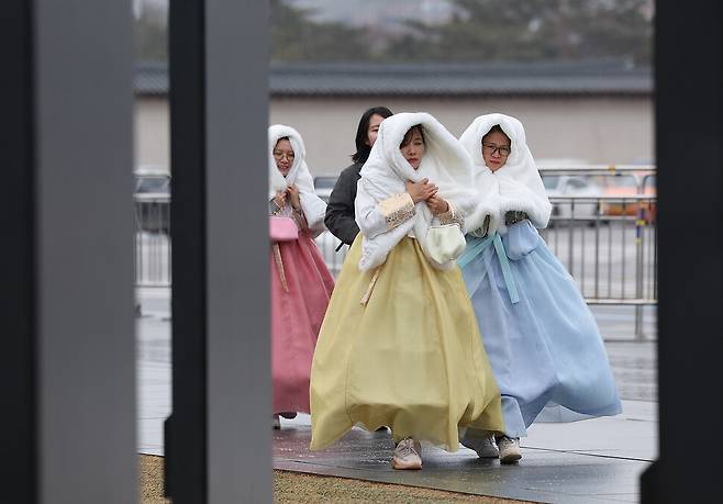 서울지역에 비가 내린 21일 오후 서울 광화문광장을 찾은 외국인 관광객들이 외투로 머리를 덮은 채 이동하고 있다. 기상청은 이날 오후 9시를 기해 서울 전역에 한파주의보를 발효한다고 밝혔다. 연합뉴스