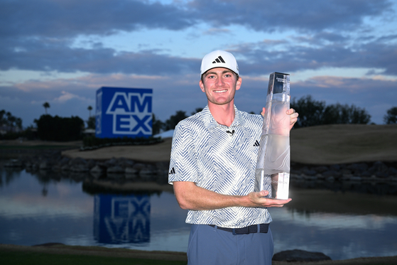 Nick Dunlap of the United States poses for a photo with the trophy after winning The American Express at Pete Dye Stadium Course in La Quinta, California on Sunday. [GETTY IMAGES]