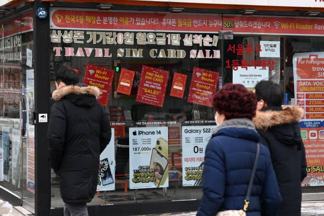 보조금 경쟁 다시 불붙나 정부가 ‘단통법’으로 불리는 이동통신단말기 유통구조 개선법 폐지를 논의하고 있는 가운데 22일 오전 단말기 할인 광고로 도배된 서울 시내의 한 이동통신 대리점 앞을 시민들이 지나가고 있다.  문호남 기자
