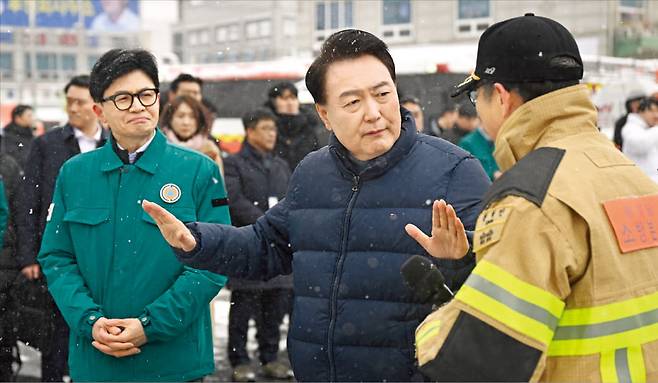 윤석열 대통령과 한동훈 국민의힘 비상대책위원장이 23일 충남 서천특화시장 화재 현장을 방문했다. 전날 밤 발생한 화재로 점포 227개가 불에 탄 현장을 점검하고 상인 지원 등 대책을 마련했다. 윤 대통령과 한 위원장이 권혁민 충남 소방본부장으로부터 피해 상황을 보고받고 얘기하고 있다.   대통령실 제공