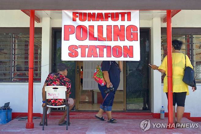 투발루 총선 (푸나푸티 AFP=연합뉴스) 25일(현지시간) 남태평양 섬나라 수도 푸나푸티에 마련된 투표소 앞을 사람들이 지나가고 있다. 2024.1.26. photo@yna.co.kr