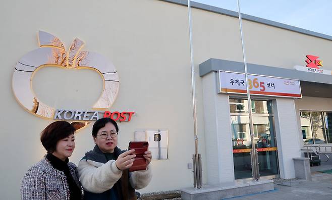 강원 정선 임계우체국 외벽에 설치된 지역 특산물 사과 조형물을 배경으로 주민들이 셀카를 찍고 있다.