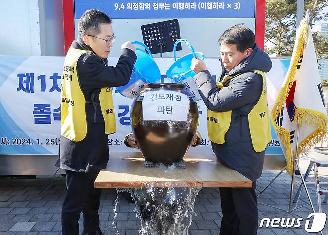 이필수 대한의사협회 회장(왼쪽)이 25일 오후 서울 용산구 전쟁기념관 앞에서 열린 '제1차 정부의 의대정원 증원 졸속추진 강력 규탄 집회'에서 의대 정원 확대로 인한 건보 재정 악화를 주장하며 '밑 빠진 독에 물 붓기' 퍼포먼스를 하고 있다. 2024.1.25/뉴스1 ⓒ News1 민경석 기자