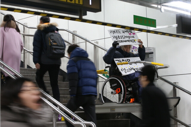 2014년 12월22일 박경석 전국장애인차별철폐연대 대표가 서울 지하철 5호선 광화문역에서 리프트에 탑승한 채 멈춰 서서 느리고 위험한 리프트 대신 서울 시내 전철역에 엘리베이터를 설치해달라고 요구하고 있다. 이정아 기자