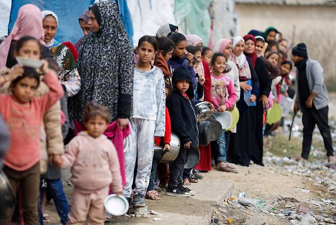 지난달 17일 팔레스타인 땅 가자지구 최남단 라파흐에서 피란민들이 음식을 배급받기 위해 늘어서 있다. 로이터 연합뉴스