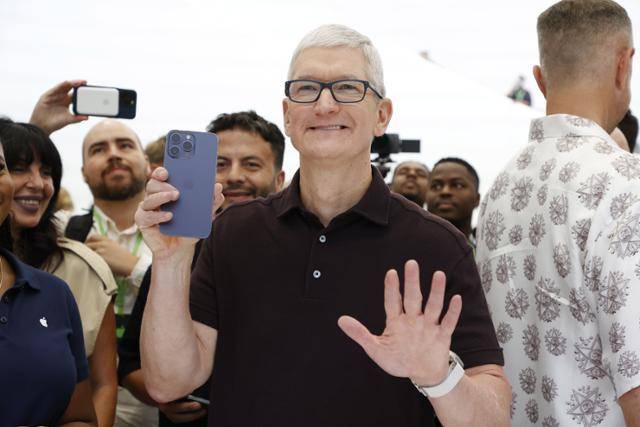 지난해 9월 아이폰15 시리즈 발표 행사를 마친 팀 쿡(가운데) 애플 최고경영자가 제품 체험 공간에서 웃으며 아이폰15를 들어 보이고 있다. 쿠퍼티노=AP 연합뉴스