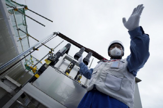 도쿄전력 관계자가 27일 일본 후쿠시마현 후타마에 있는 후쿠시마 제1원자력발전소에서 희석을 완료한 오염수(일본 정부 명칭 '처리수')의 샘플을 채취하는 기계를 기자들에게 설명하고 있다. 사진=연합뉴스