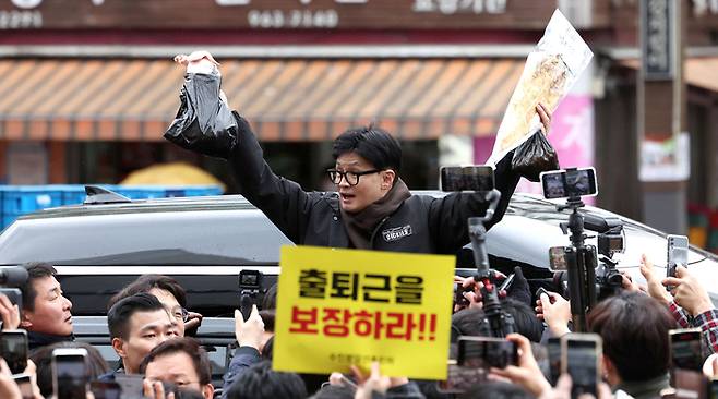 국민의힘 한동훈 비상대책위원장이 설 명절 연휴를 나흘 앞둔 5일 서울 동대문구 청량리 청과물시장·경동시장을 방문해 구매한 상품을 들어보이며 시민들과 인사를 나누고 있다. [사진 = 연합뉴스]