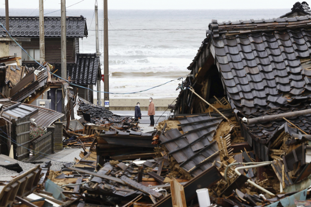 지난달 10일 일본 이시카와현 와지마시에서 주민들이 무너진 주택을 돌아보고 있다. 연합뉴스