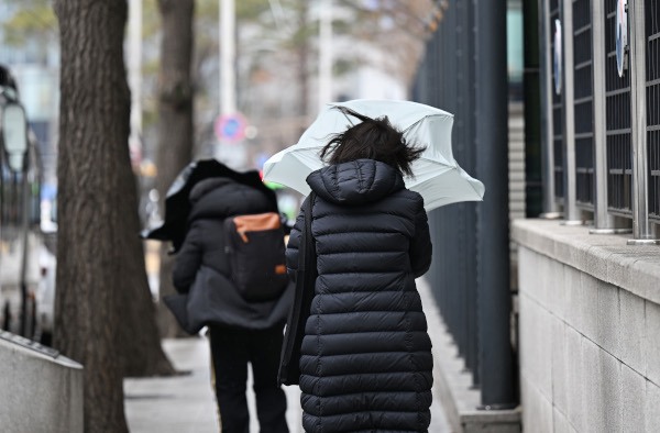 전국에 비와 눈이 내린 5일 서울 광화문광장에서 시민들이 우산으로 눈과 바람을 막으며 걸어가고 있다. 6일에는 전국 아침 기온이 뚝 떨어지고 강풍이 불 전망이다. 이한형 기자