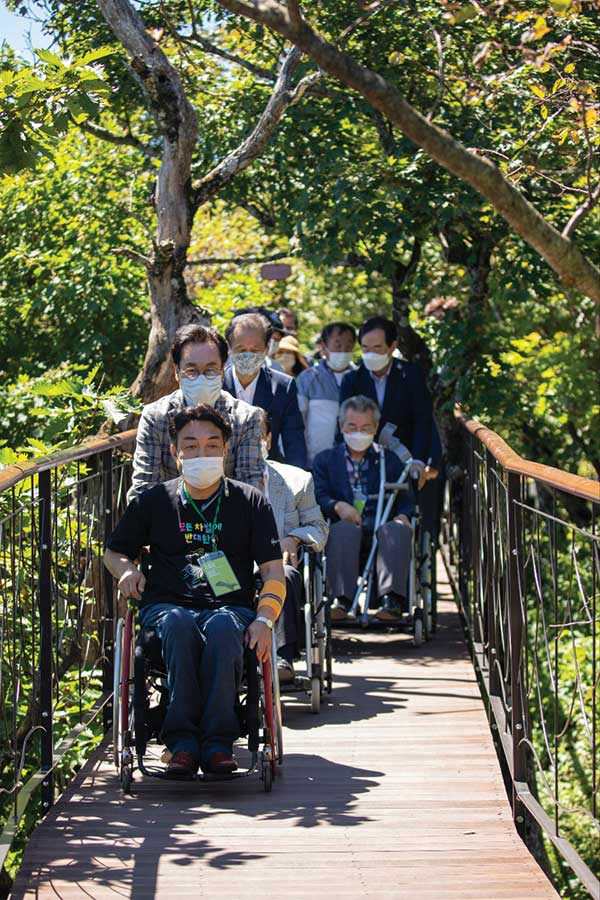 지난 2020년 모나 용평과 강원도가 도내 장애인을 초청한 천년주목숲길 체험 행사에서 신달순 대표와 최문순 전 지사가 휠체어를 밀고 있다. 이 길은 장애인도 휠체어를 타고 3.2km를 탐방할 수 있도록 설계했다