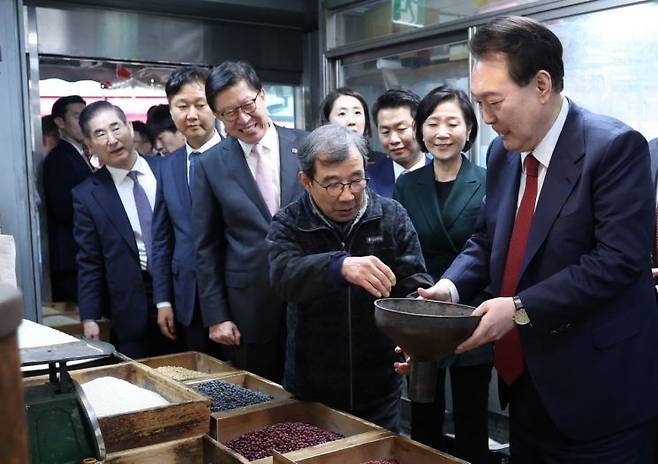 윤석열 대통령이 13일 오후 부산 동래구 동래시장의 쌀가게를 방문해 깔때기를 들고 상인과 대화하고 있다. [이미지출처=연합뉴스]