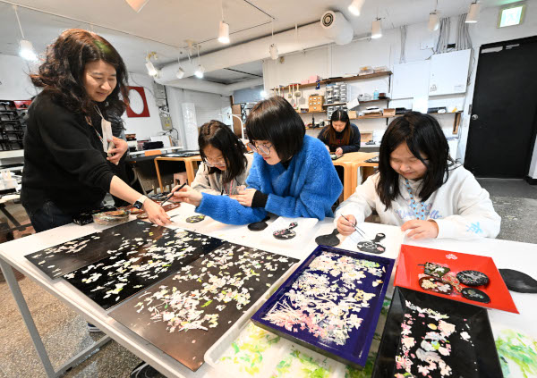 서울 북촌마을 진주쉘 매장에서 지난 8일 방문객들이 자개로 손거울을 만들고 있다.