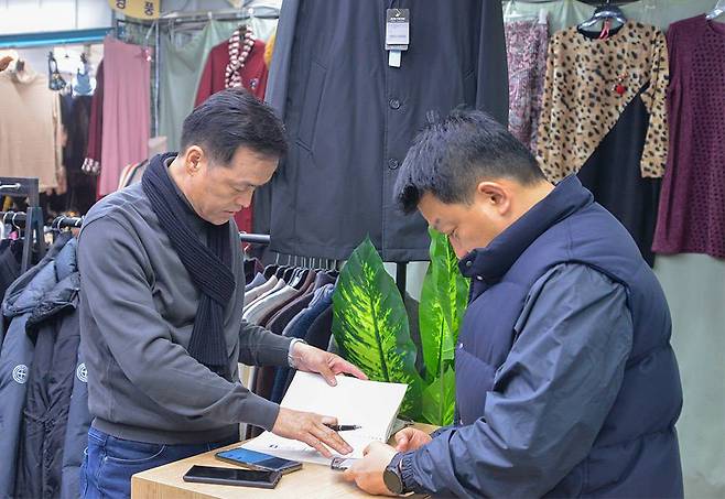정승호 대표가 시장 상인과 거래 내역을 확인하고 있다 / 출처=IT동아
