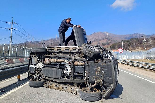 17일 강원도 횡성군 한 국도에 넘어진 사고 차량에서 퇴근길 경찰관과 시민이 운전자를 구조하는 모습. /횡성경찰서