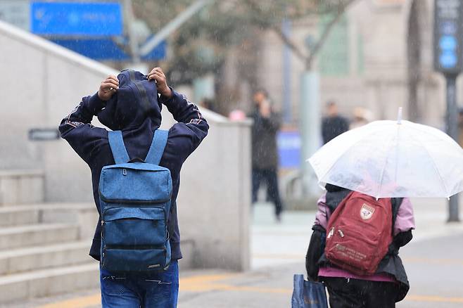 전국 곳곳에 비가 내린 18일 오후 서울역 인근에서 시민이 겉옷에 달린 모자로 비를 막으며 이동하고 있다. 연합뉴스