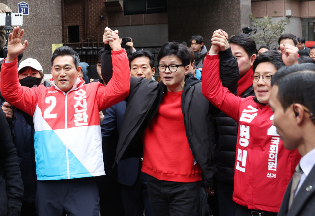 한동훈(앞줄 가운데) 국민의힘 비상대책위원장이 20일 서울 광진구 화양동에서 '시민이 안전한 대한민국' 현장 공약 발표에 앞서 오신환(왼쪽) 광진을 후보와 김병민 광진갑 후보의 손을 번쩍 들고 있다. 연합뉴스