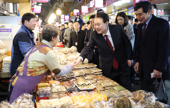 President Yoon Suk Yeol, center, visits a vendor at Sinjeong Market, a traditional market in Ulsan, after holding the 13th public livelihood debate in the port city earlier that day. [JOINT PRESS CORPS]