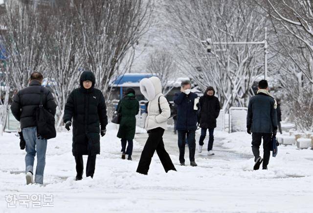 22일 서울 종로구 광화문에서 시민들이 눈 쌓인 도로를 따라 조심스레 출근하고 있다. 왕태석 선임기자