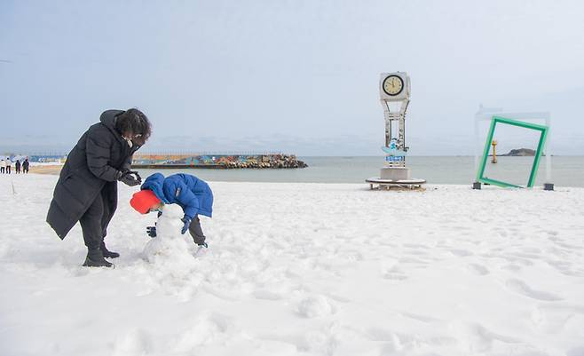 강원 고성 지역에 많은 눈이 내린 가운데 25일 고성군 천진해수욕장에서 관광객들이 눈사람을 만들고 있다. 연합뉴스.