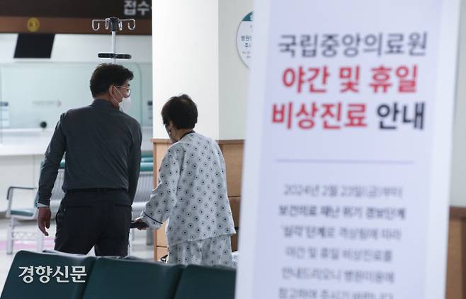 보건의료 위기단계 ‘심각’으로 상향…비상진료 시작한 국립중앙의료원 정부의 의과대학 정원 확대에 반발한 전공의 파업으로 보건의료재난 위기경보가 ‘심각 단계’로 상향된 25일 서울 중구 국립중앙의료원에 놓인 야간 및 휴일 비상진료 안내문 너머로 환자와 보호자의 모습이 보인다. 국립중앙의료원은 평일 오후 5시30분~8시, 휴일 오전 9시~낮 12시 비상진료를 운영한다. 성동훈 기자 zenism@kyunghyang.com