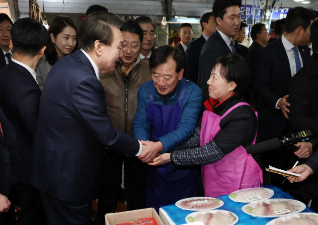 윤석열 대통령이 26일 충남 서산 동부 전통시장을 찾아 활어 매장에서 상인과 인사하고 있다. 대통령실통신사진기자단=연합뉴스