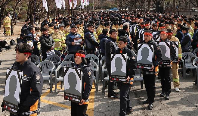 전국공무원노동조합 소방본부 소속 소방관들이 26일 오후 서울 영등포구 여의도 KDB산업은행 본점 앞에서 열린 총궐기대회에서 최근 순직한 소방관들의 영정을 들고 입장하고 있다. 신소영 기자