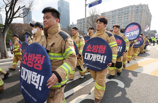 전국공무원노동조합 소방본부 소속 소방관들이 26일 오후 서울 영등포구 여의도 KDB산업은행 본점 앞에서 열린 총궐기대회에서 열어 소방 인력 증원과 소방 조직 국가직화 등을 촉구한 뒤 더불어민주당과 국민의힘을 향해 행진하고 있다. 신소영 기자