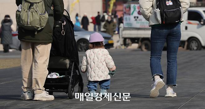 걸음마를 시작한 아기가 아빠와 함께 걷고 있다. 남성 육아휴직이 늘면서 유모차 끄는 아빠를 보는 일도 낯설지 않게 됐다. [이충우 기자]