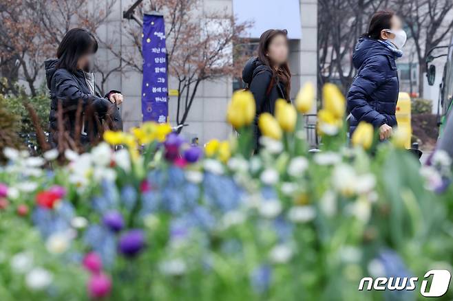 3·1절 연휴에 '꽃샘 추위'가 한반도를 덮친다. 기상청에 따르면 1일에는 아침 최저 기온이 영하 7도, 2일은 영하 9도까지 내려가겠다. 29일 오전 서울 성동구 왕십리광장 화단 너머로 겨울 외투를 챙겨입은 시민들이 오가고 있다. 2024.2.29/뉴스1 ⓒ News1 민경석 기자