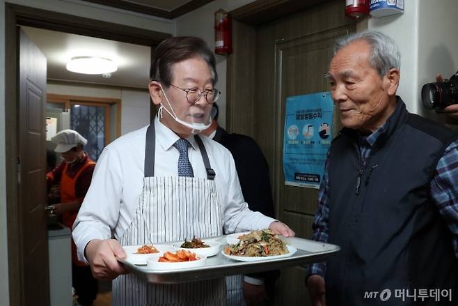 [서울=뉴시스] 국회사진기자단 = 이재명 더불어민주당 대표가 21일 오전 서울 영등포구 구립 큰숲 경로당에서 어르신들에게 배식 봉사를 하고 있다. 이 대표는 식사를 마친 후 주5일 점심 제공 정책 간담회에 참석했다. 2023.12.21. photo@newsis.com /사진=조성봉