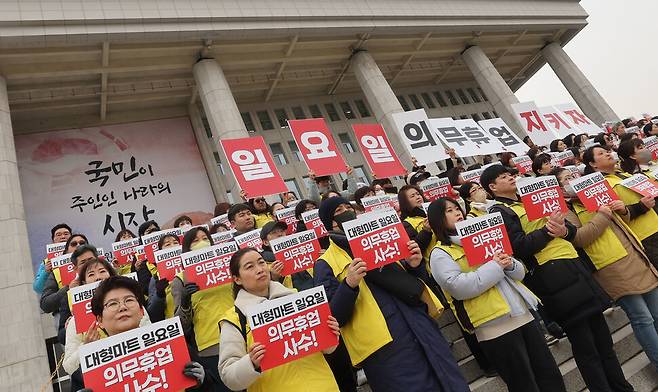 마트노동자들이 5일 오전 서울 영등포구 국회의사당 본청 앞에서 기자회견을 열어 일요일 의무휴업 사수가 적힌 손팻말을 들고 있다. 백소아 기자