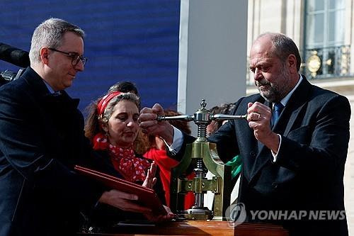 (파리 AFP=연합뉴스) 에리크 뒤퐁 모레티 프랑스 법무부 장관이 8일(현지시간) 시내 방돔 광장에서 낙태할 자유가 명시된 헌법 개정안에 국새를 날인하고 있다. 2024.03.08.