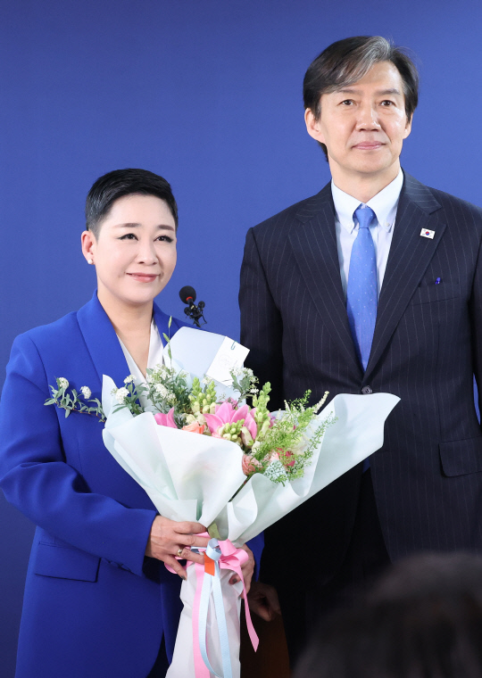 가수 리아(본명 김재원)가 11일 여의도 조국혁신당 당사에서 열린 입당 환영식에서 조국 대표로부터 꽃다발을 받고 포즈를 취하고 있다.   [연합뉴스]