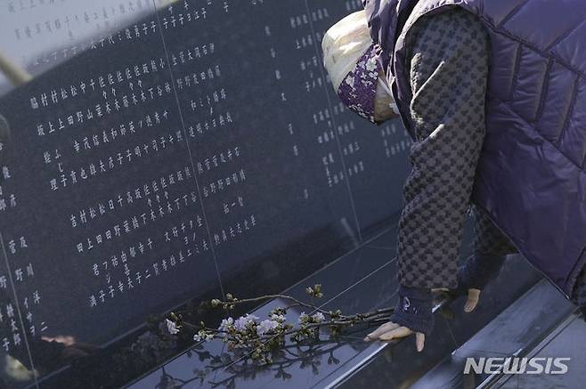 [이와테=AP/뉴시스]일본 동일본대지진 13주기를 맞이한 11일 이와테현 리쿠젠타카타 희생자들 기념비 앞에서 한 여성이 행방불명된 딸에게 꽃을 바치며 눈물을 흘리고 있다. 2024.03.11.