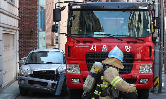 서울시 소방재난본부 소속 소방관들이 소방활동 방해 주차차량 '강제처분' 훈련을 하며 통행로를 막은 불법 주차차량을 소방차로 파손하며 출동하는 연습을 하고 있다. 연합뉴스