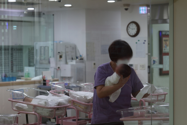 지난달 28일 서울 시내 한 산후조리원 신생아실에서 한 관계자가 신생아를 돌보고 있다. 연합뉴스
