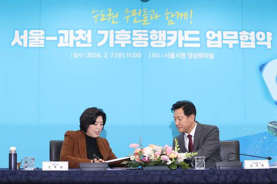 Seoul Mayor Oh Se-hoon, right, and Gwacheon Mayor Shin Gye-yong sign an agreement to expand the Climate Card scheme to the southern Gyeonggi city at City Hall in downtown Seoul on Wednesday. [YONHAP]