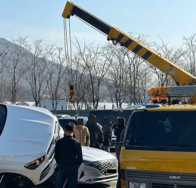 지난 13일 서울 만남의광장 휴게소에서 발생한 주차 사고 수습을 위해 크레인이 그랜저 차량을 들어 올리고 있다./온라인커뮤니티