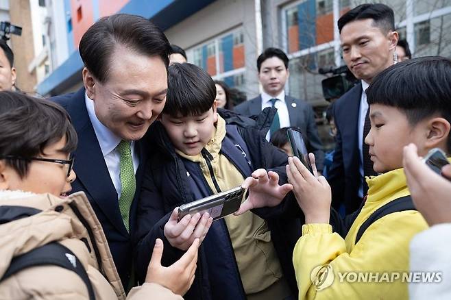 윤석열 대통령이 14일 전남 무안군 오룡초등학교 도서관에서 늘봄학교 간담회를 마친 뒤 학교를 떠나며 학생들과 기념사진을 찍고 있다. [대통령실 제공]