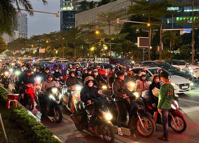 베트남 수도 하노이 시내 퇴근길 풍경. 헬멧과 마스크를 착용한 여성들이 남성들 틈에 끼어 오토바이로 퇴근하고 있다. 하노이=허경주 특파원