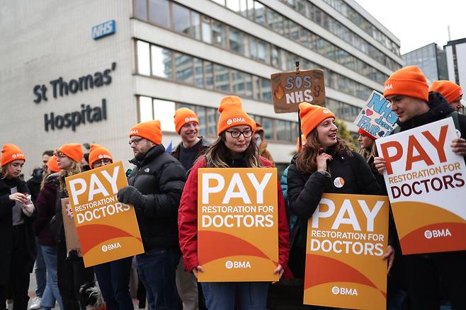 영국 의료진이 지난달 24일 정부가 10년 차 이하 주니어 의사들의 임금을 삭감한 것에 항의하는 플래카드를 들고 런던 세인트토머스 병원 앞에서 파업 시위를 하고 있다. /EPA 연합뉴스