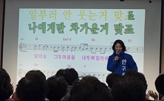 안귀령 더불어민주당 서울 도봉갑 후보가 지역의 한 노래교실에서 선거운동복을 입고 "잘 부탁드린다"며 노래를 부르고 있다.